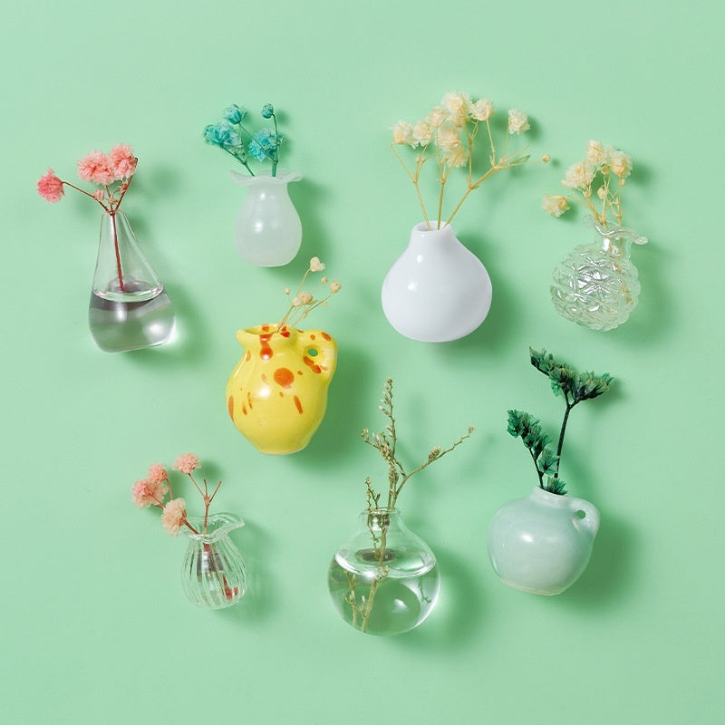 Collection of small vases with plants on a light green background