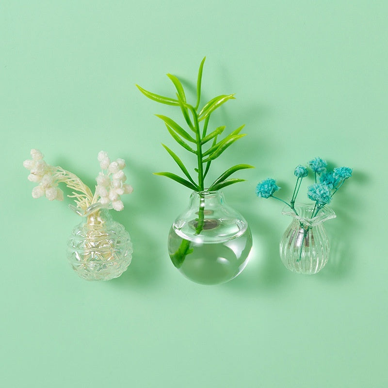 Three small glass vases with plants on a light green background