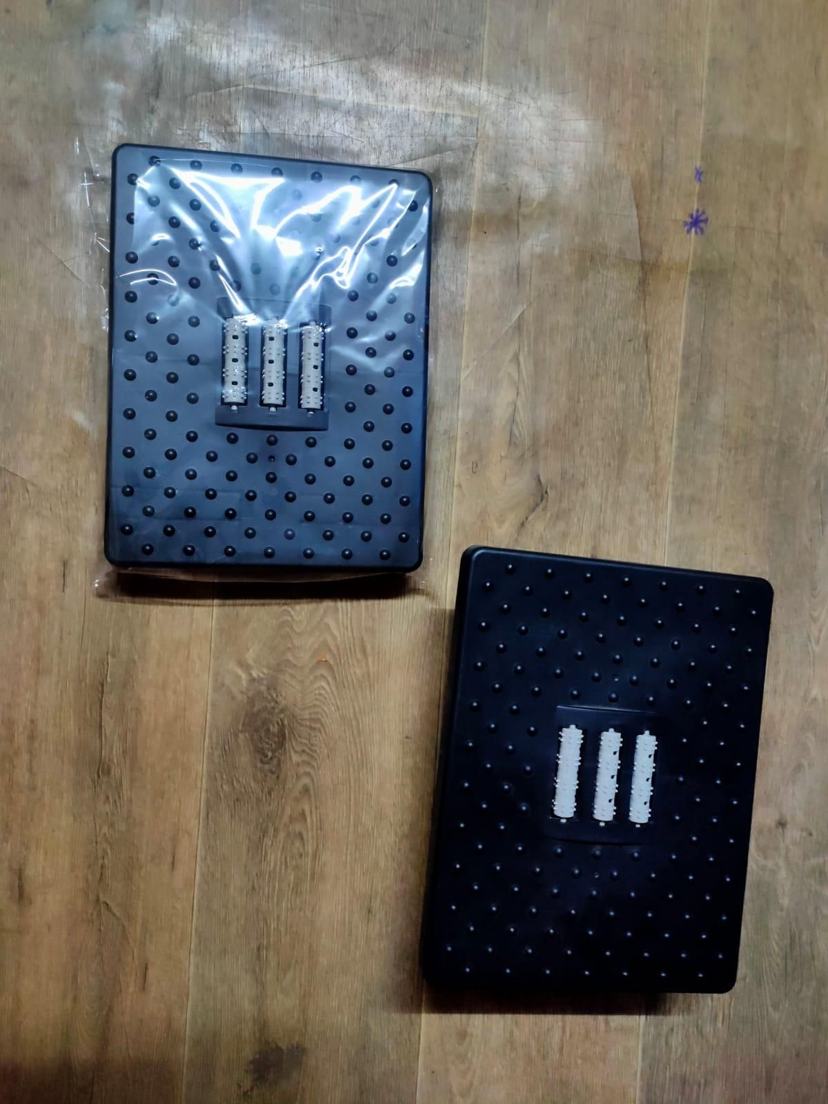 Two black textured mats with a brand logo on a wooden surface