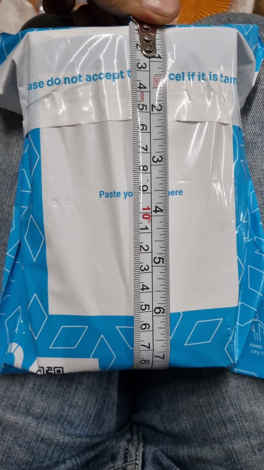 Measurement of a package with a ruler, showing dimensions on a textured surface.