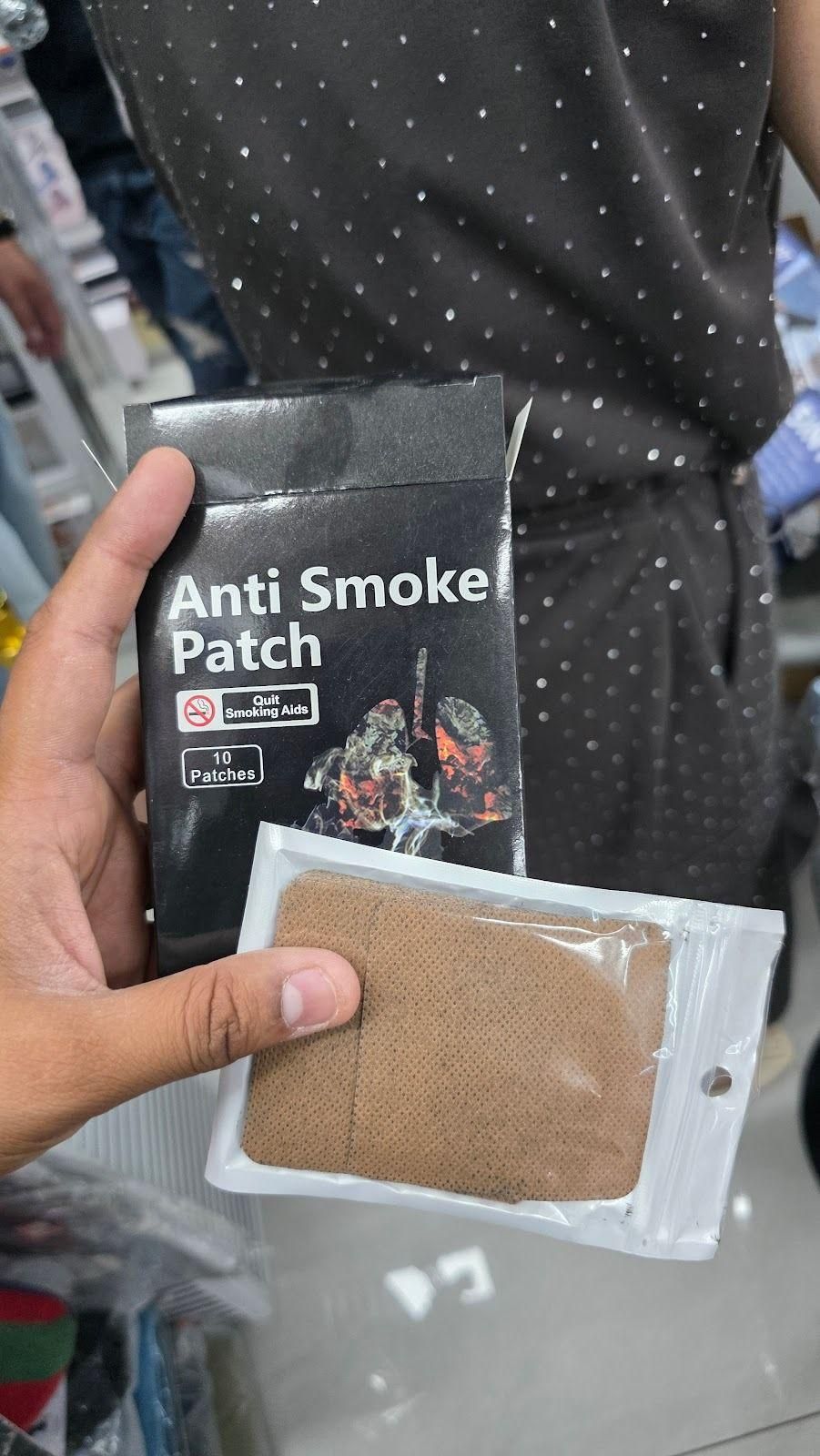 Hand holding anti-smoke patches with packaging in a store setting