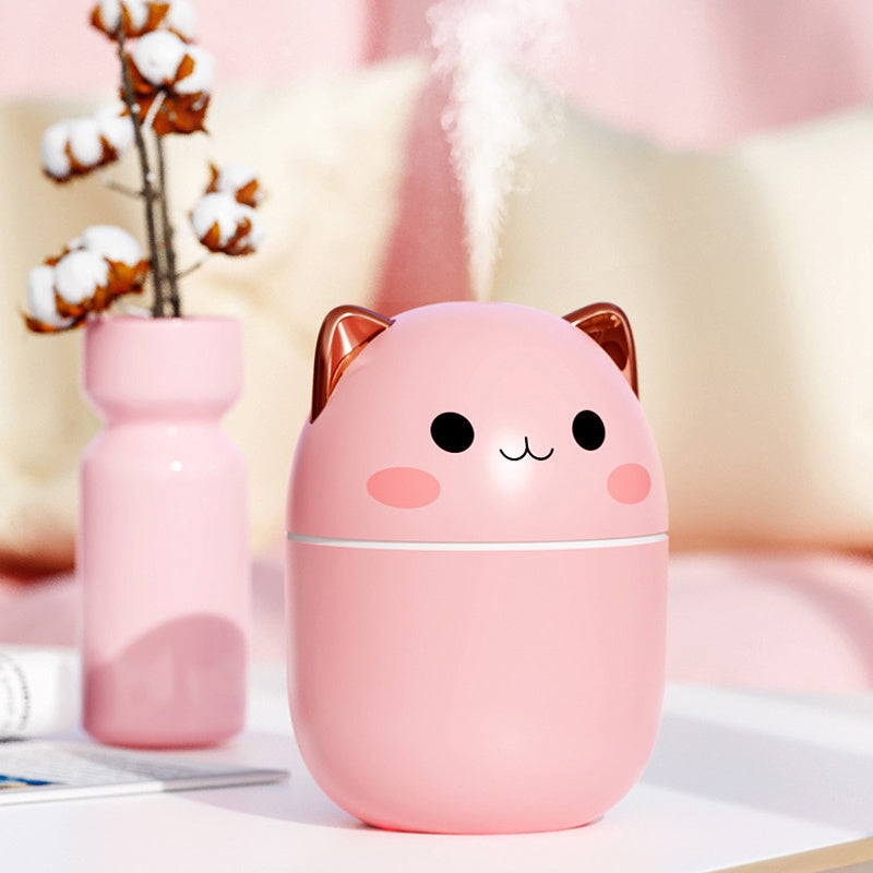 Pink cat-shaped humidifier on a blurred background with cotton plants and books.
