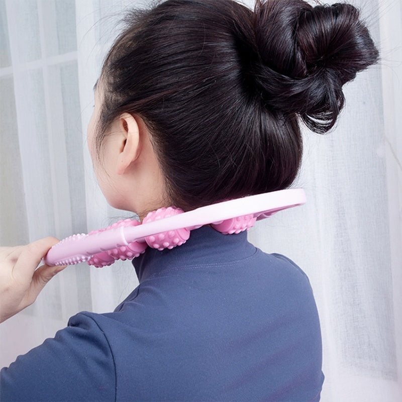 Person using a pink neck and shoulder massager against a white curtain background