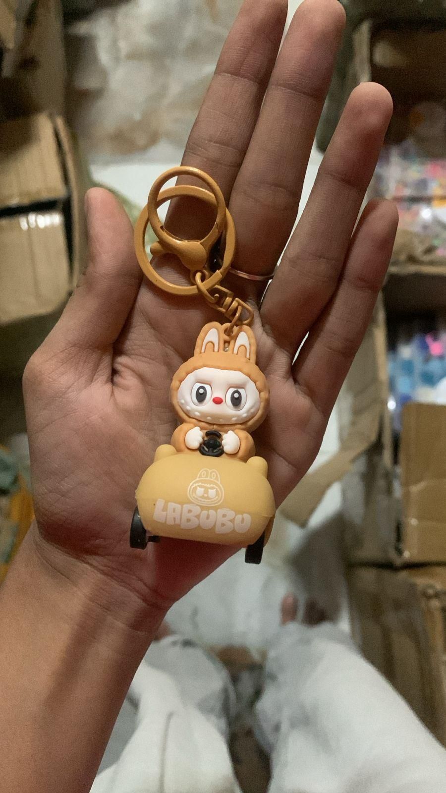 Hand holding a cartoon character keychain with a blurred background