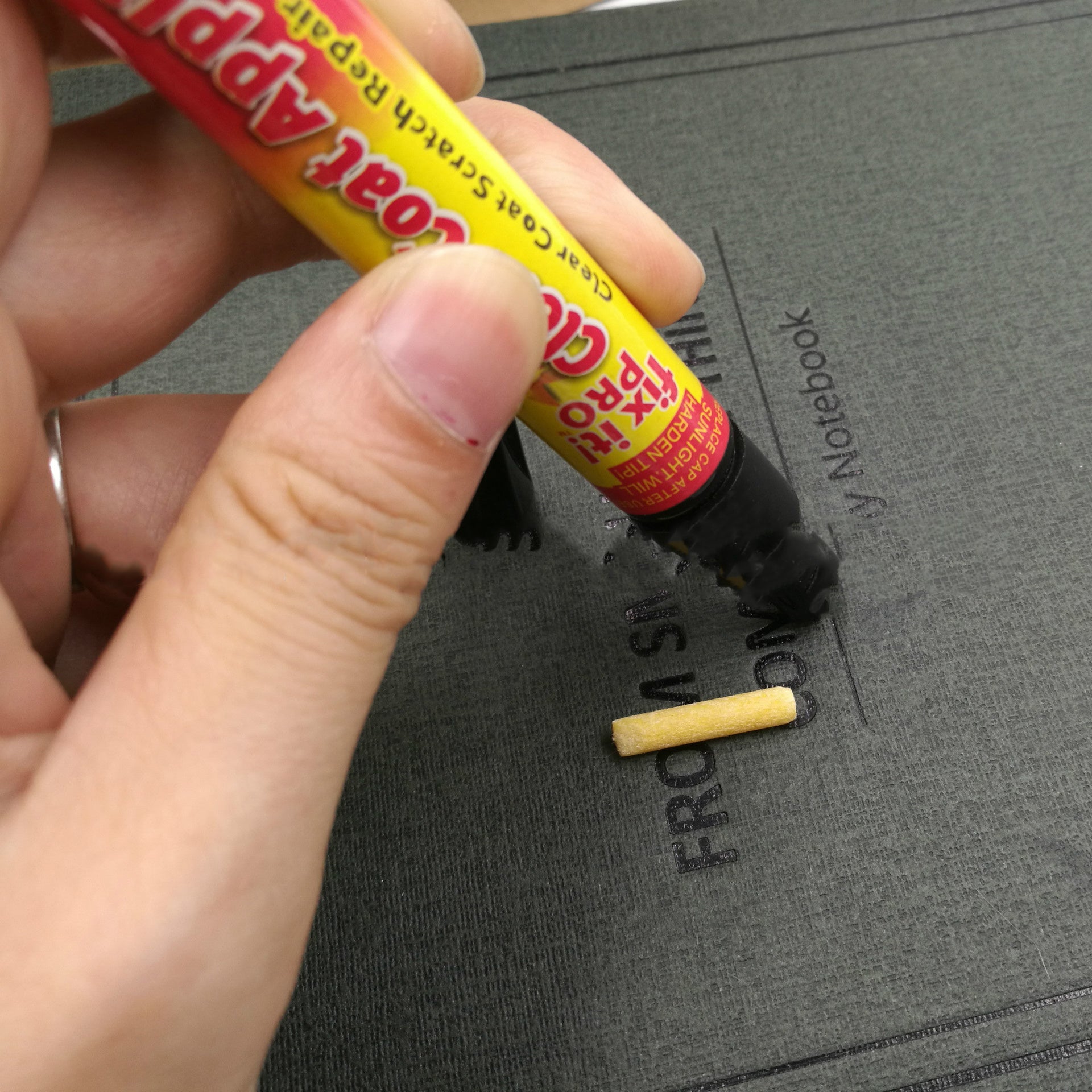 Person applying a product to a gray notebook with a visible brand name.