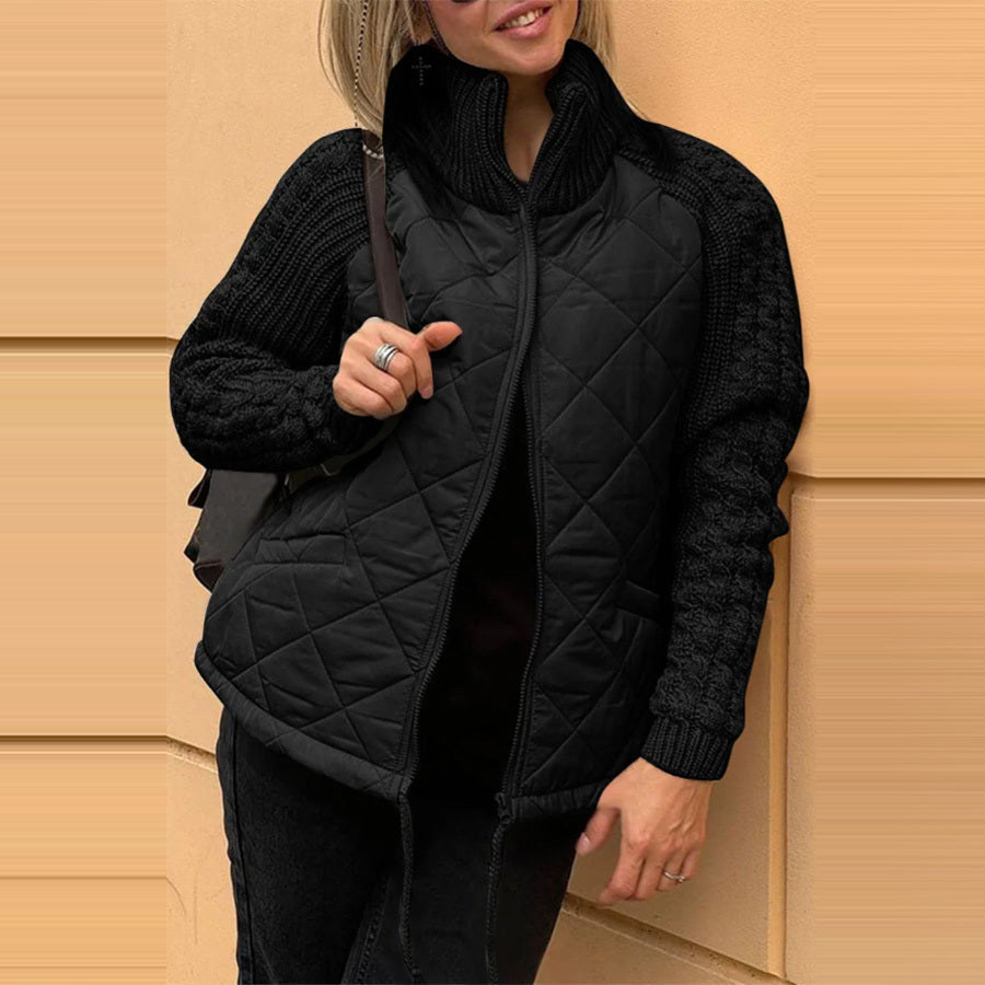 Person wearing a black quilted jacket against a beige wall