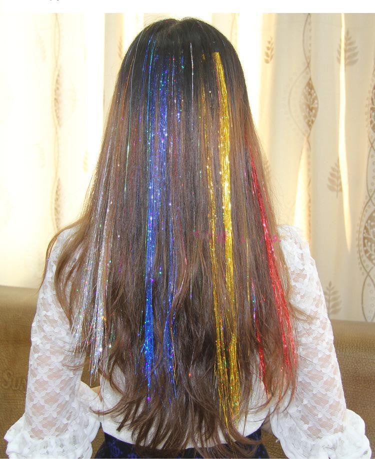 Person with multicolored hair extensions in a room with curtains.