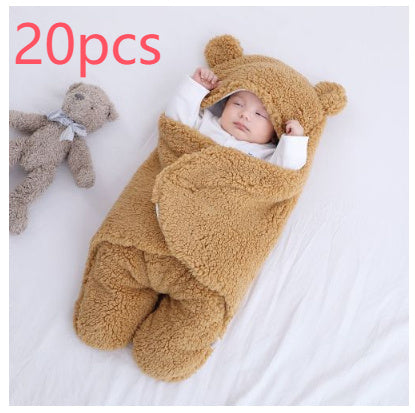 Baby in a brown bear-themed sleeping bag with a teddy bear on a white background