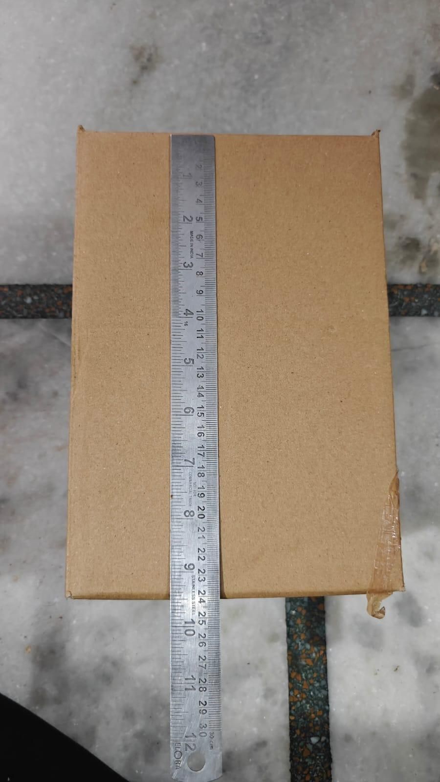 Cardboard box with a ruler for scale on a concrete floor