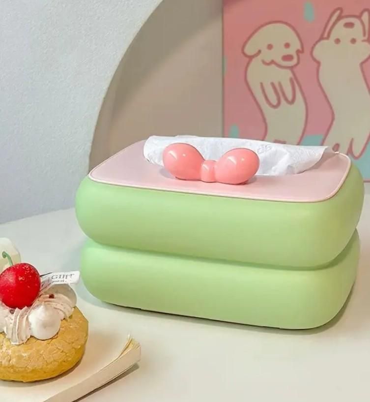 Green and pink tissue holder with a donut on a white surface