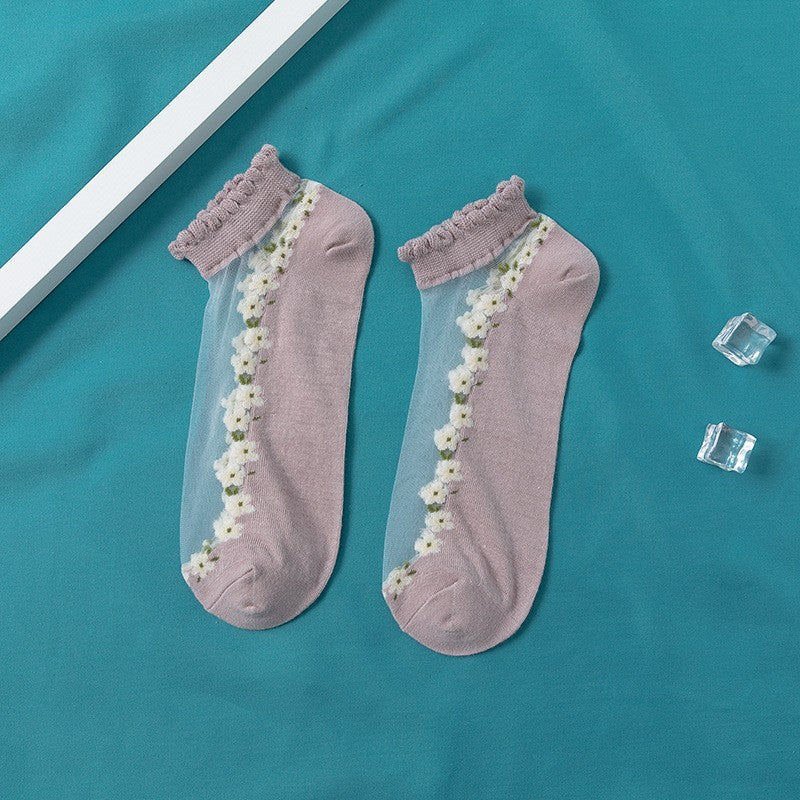 A pair of women's boat socks with a floral design in purple and white colors, worn with a pair of flat shoes.