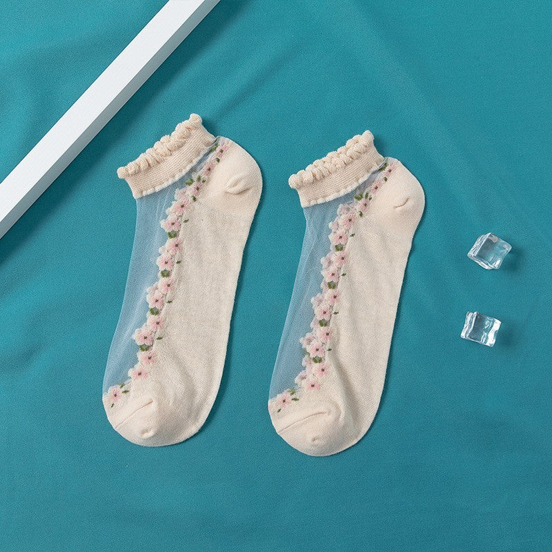 A pair of women's boat socks with a floral design in purple and white colors, worn with a pair of flat shoes.
