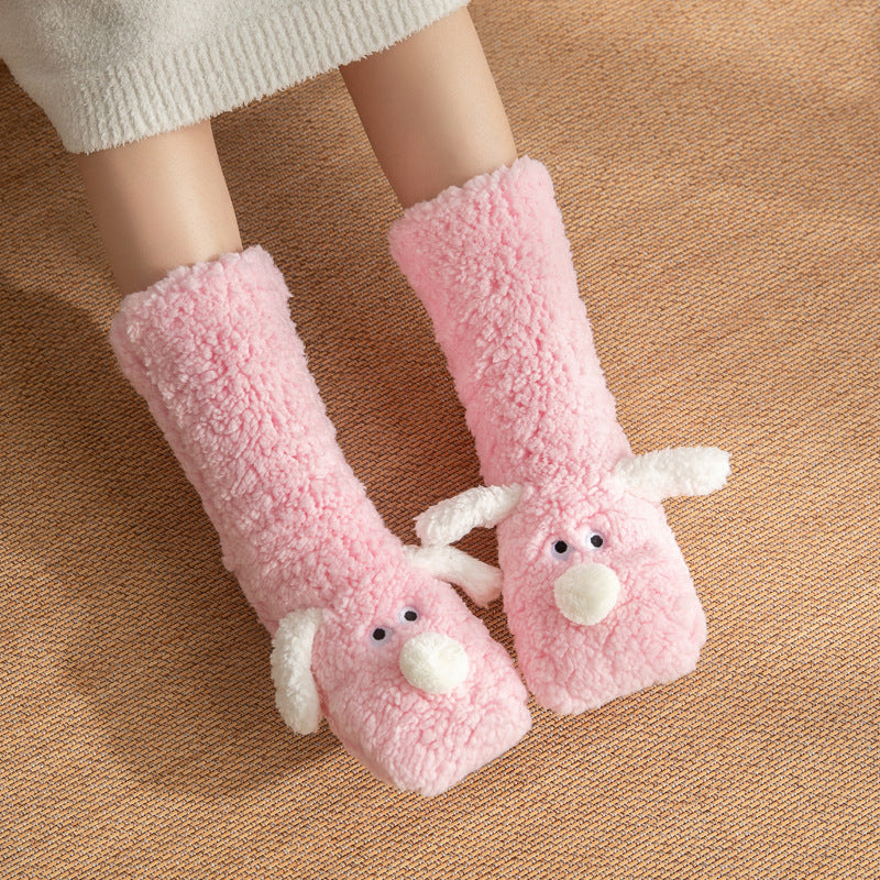 Pink plush slippers with animal faces on a brown surface