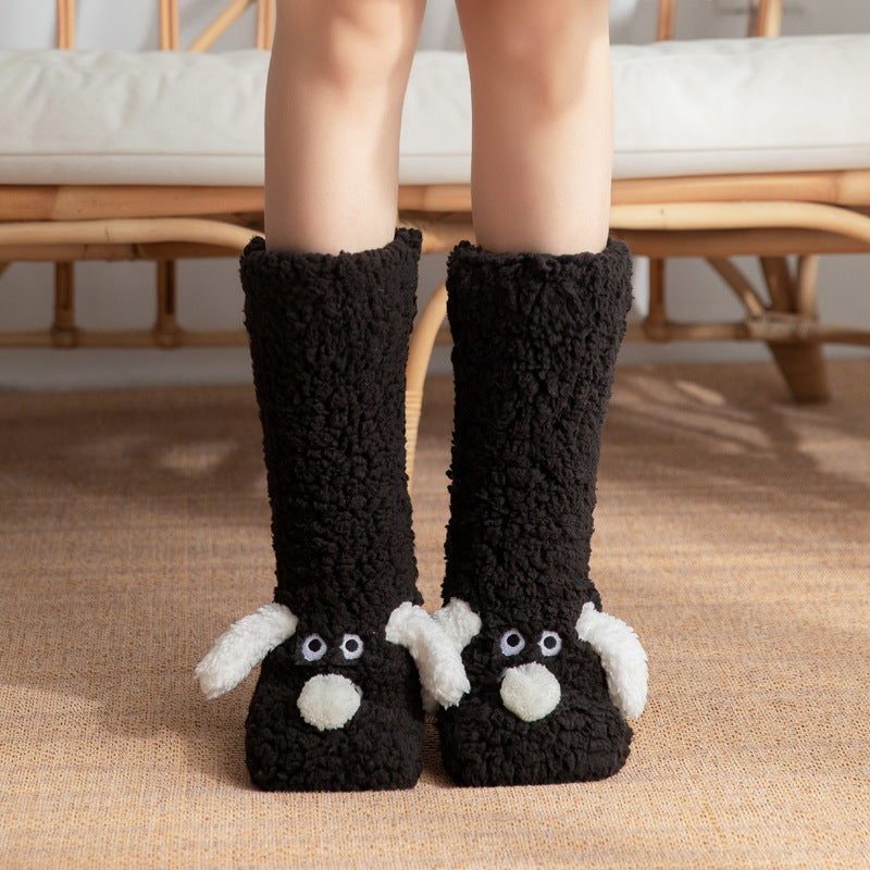 Black knitted slippers with sheep design worn by a person indoors.