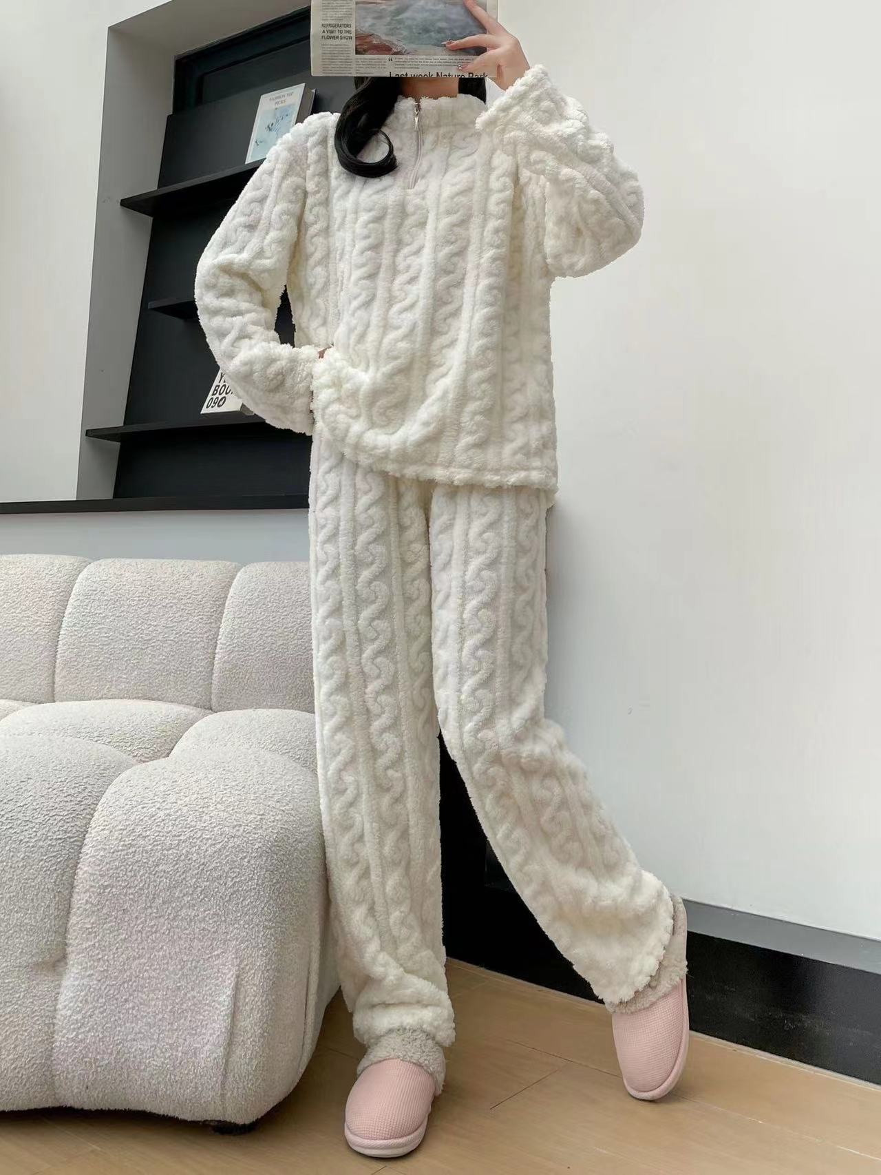 Person wearing a white cable-knit pajama set with pink slippers in a minimalistic room.