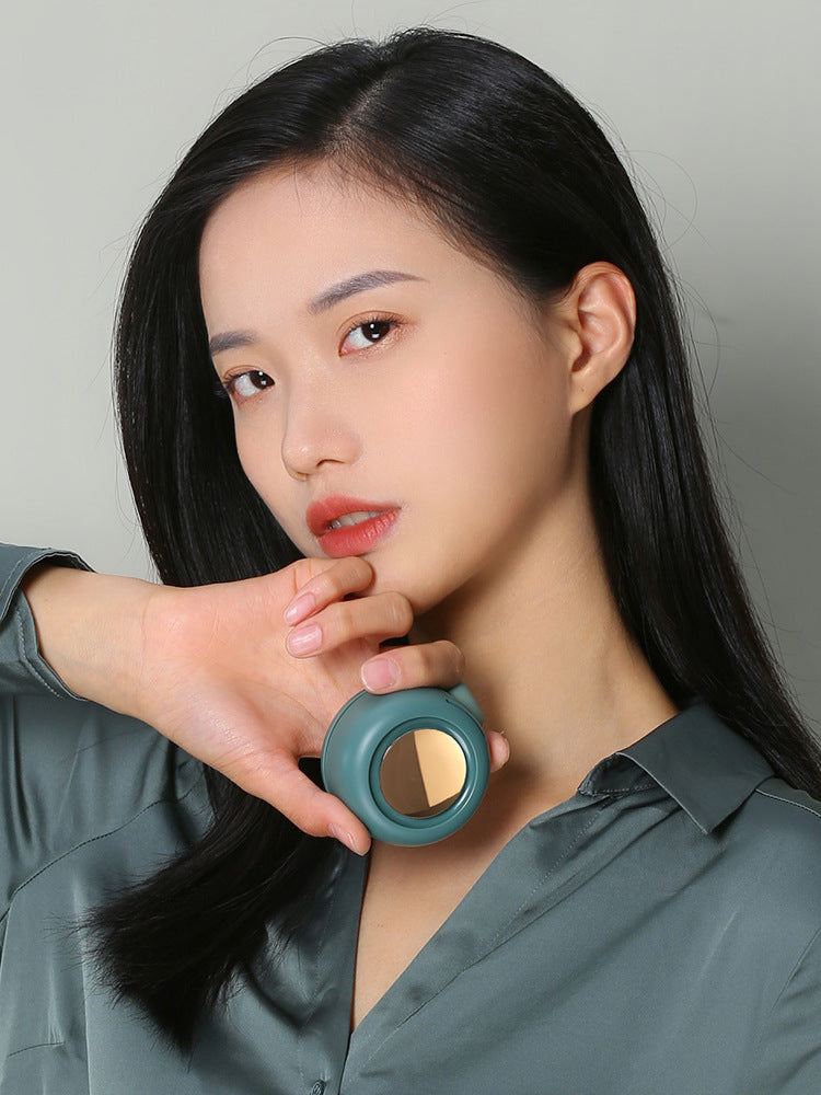 Woman wearing a teal necklace with a reflective pendant against a gray background