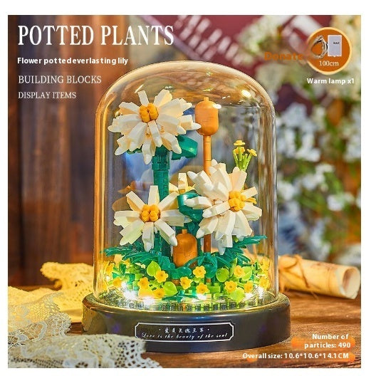 Decorative potted plant made of building blocks with a warm lamp inside, on a wooden surface.