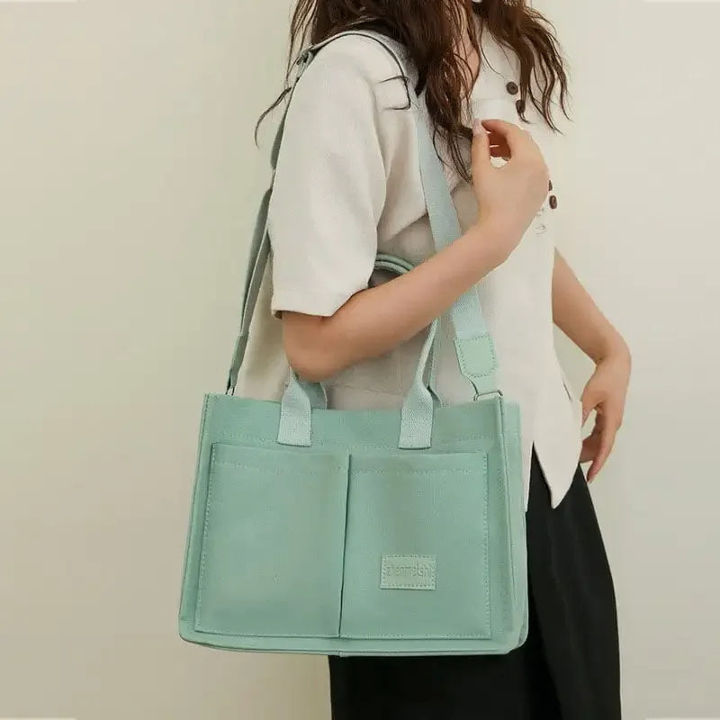 Person holding a light blue tote bag against a neutral background