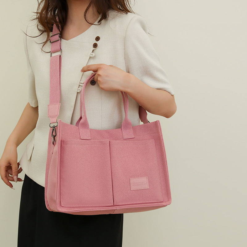 Person holding a pink tote bag against a neutral background