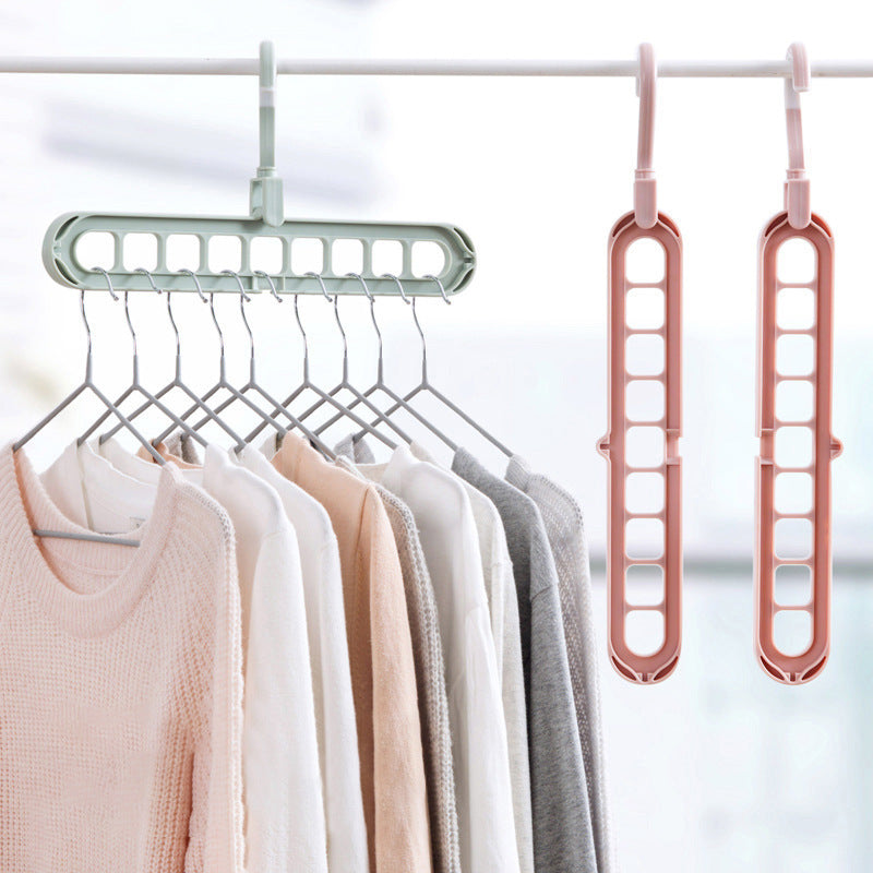 Multi-functional hanger with clothes on a rack and two pink hangers on a white background