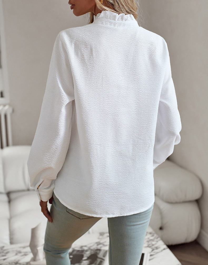 Person wearing a white textured blouse in a neutral indoor setting