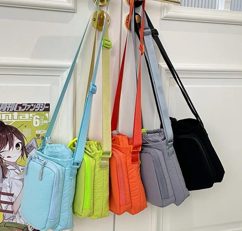 Colorful small bags hanging on a hook against a white wall.