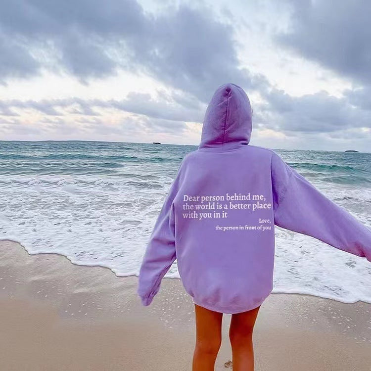 Person wearing a purple hoodie with a message on the beach