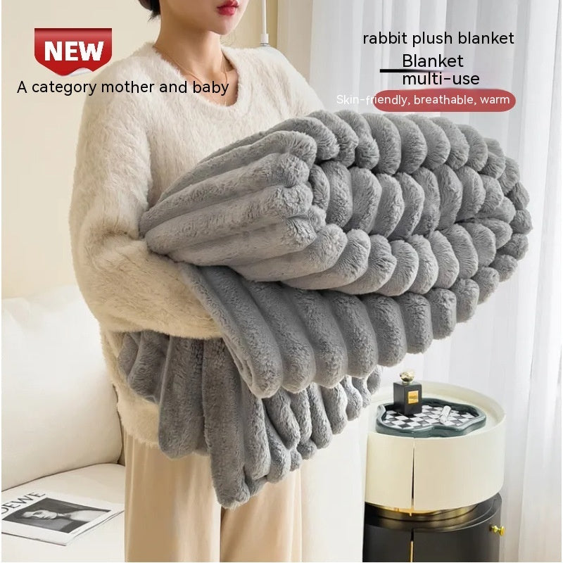 Person holding a gray plush blanket with product details on a blurred background