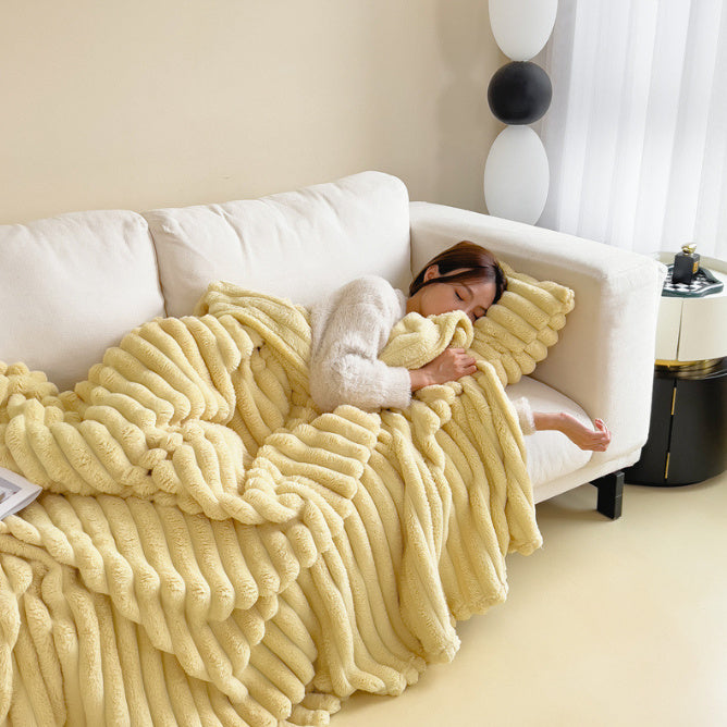 Person lying on a white couch under a yellow textured blanket in a cozy living room.