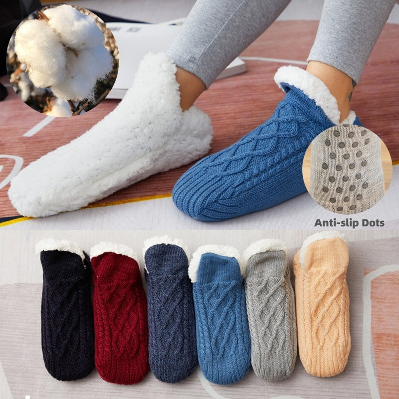 Pair of blue cable knit socks with white sherpa lining on a wooden floor, surrounded by other colors of similar socks.