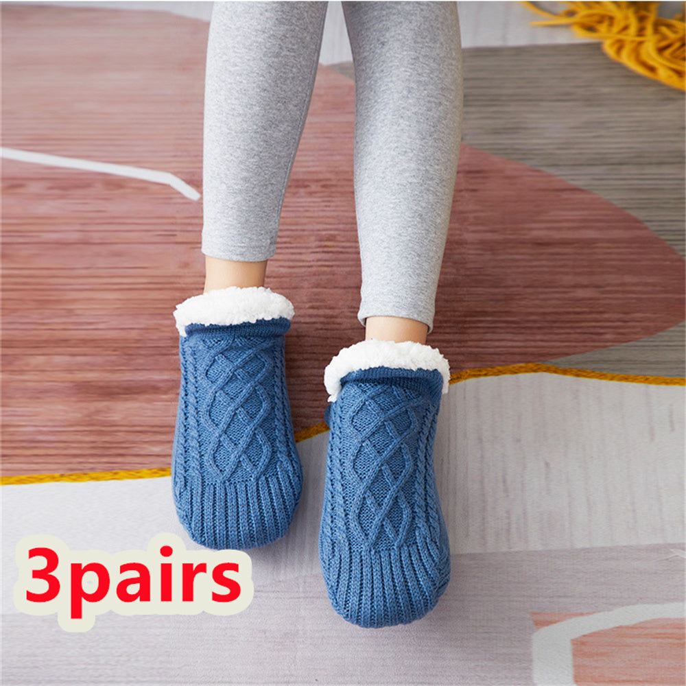 Blue knitted socks with white fur lining worn by a person on a wooden floor.