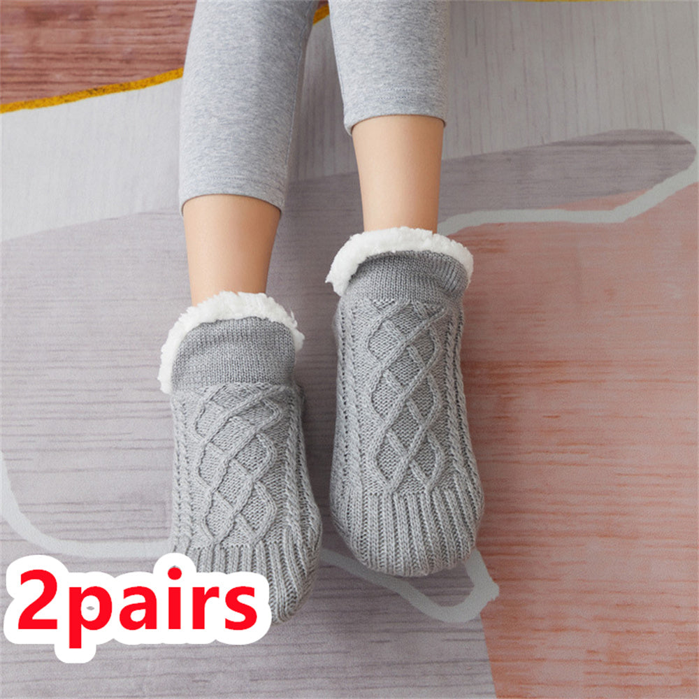 Gray cable knit socks with white fleece lining worn by a person on a wooden floor.