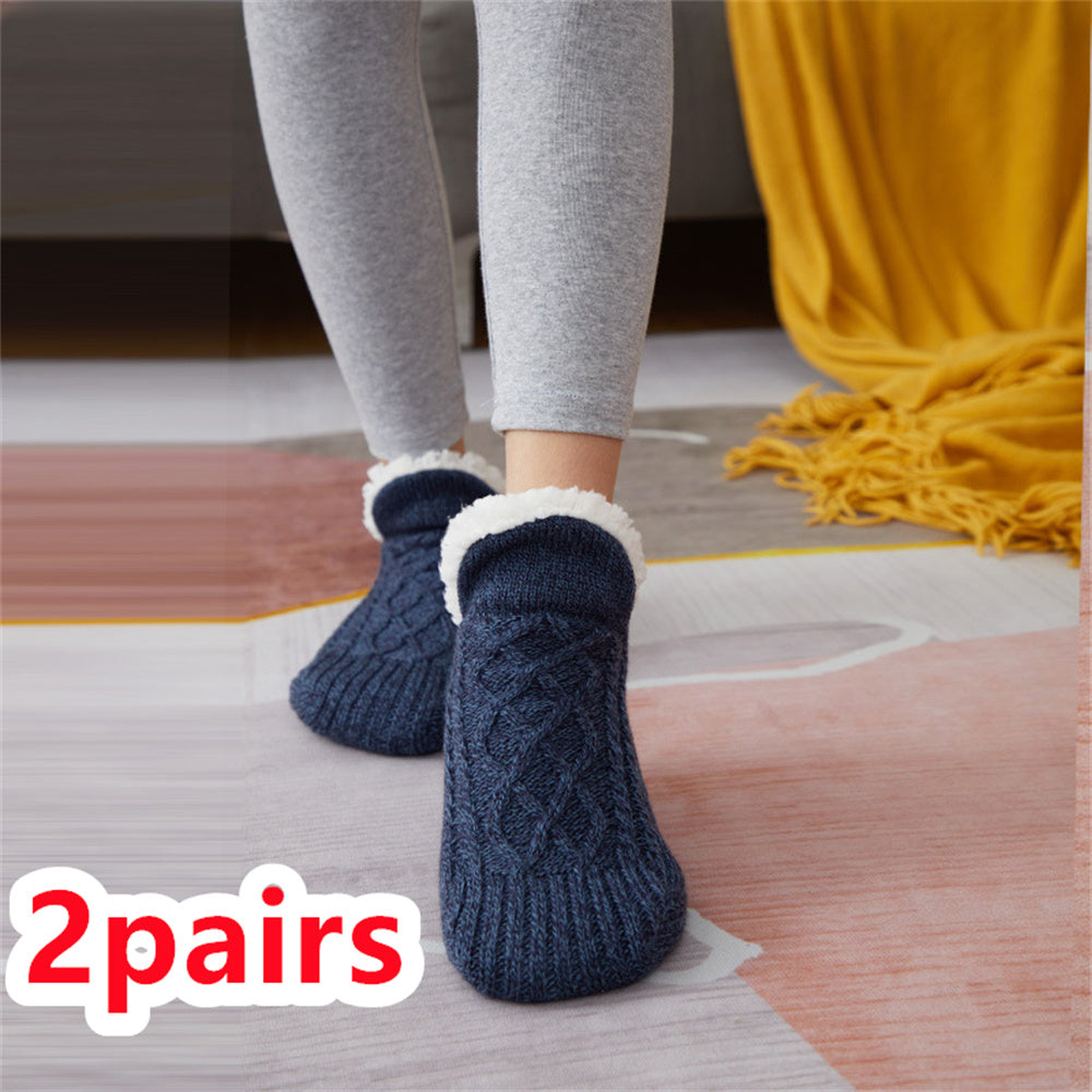 Person wearing blue cable knit socks with white cuffs on a wooden floor.