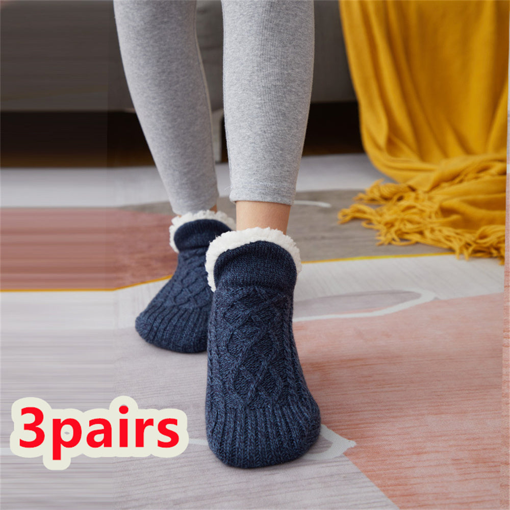 Person wearing blue cable knit socks with white cuffs on a wooden floor.