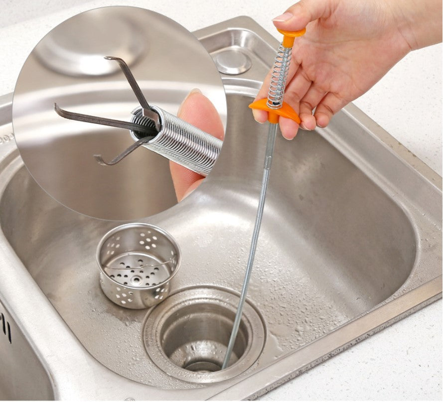 Person using a kitchen sink drain cleaning tool in a stainless steel sink.