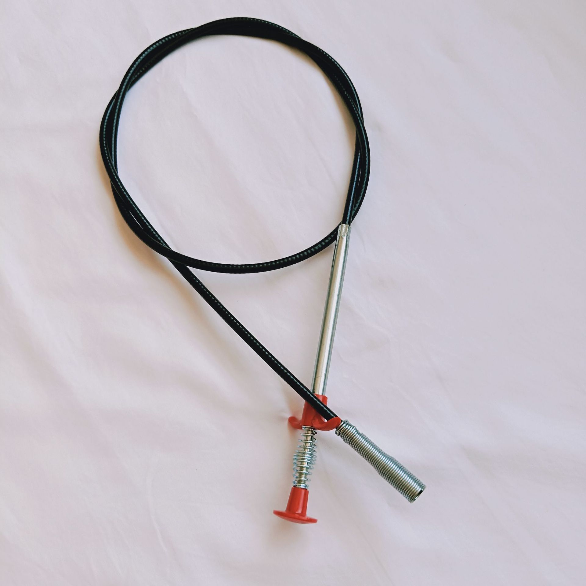 Black cable with metal end and red plastic housing on a light pink background