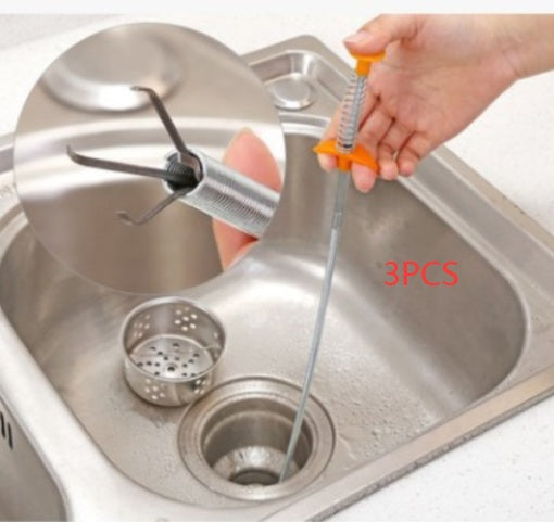 Stainless steel sink drain cleaning tool being used in a kitchen sink.
